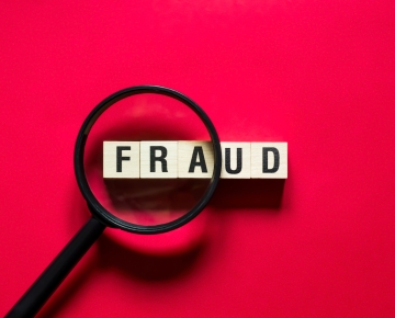 fraud letters with magnifying glass and red background