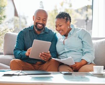 couple looking at papers and tablet on the couch