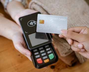 Credit card over handheld point of sale terminal. 