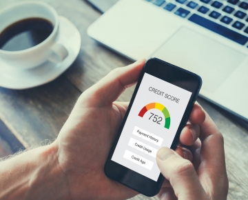 Person holding phone displaying credit score. 