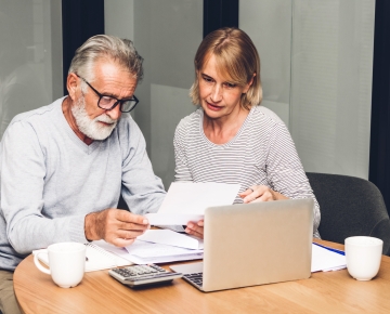 Concerned couple with laptop and paperwork