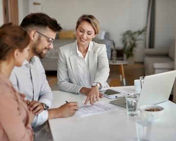couple signing papers with woman in office