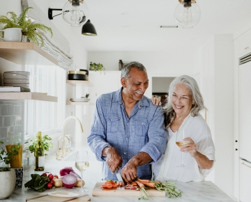 couple cooking together, with man in blue shirt and woman in white shirt