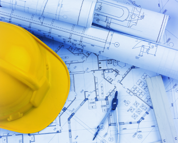 yellow construction hat on top of blueprints