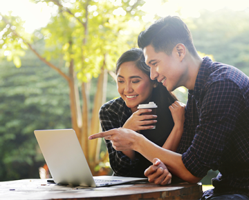 couple looking at laptop with greenery in the background