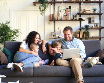 family sitting on the couch looking at a laptop