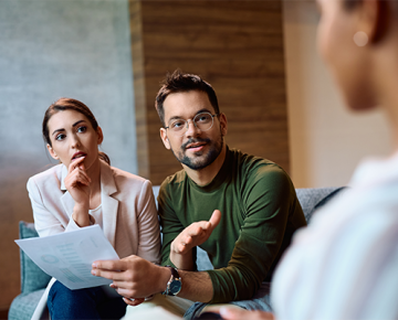 couple holding paper and talking to real estate agent